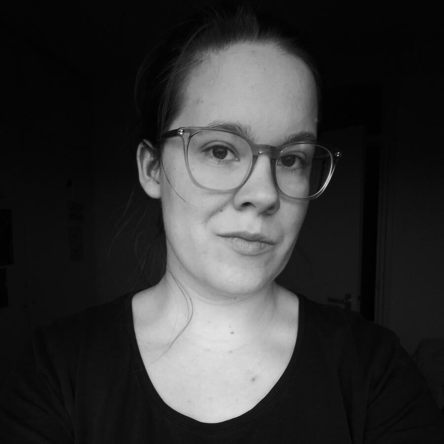 A black and white photography of a white person with glasses wearing a black shirt with long sleeves.